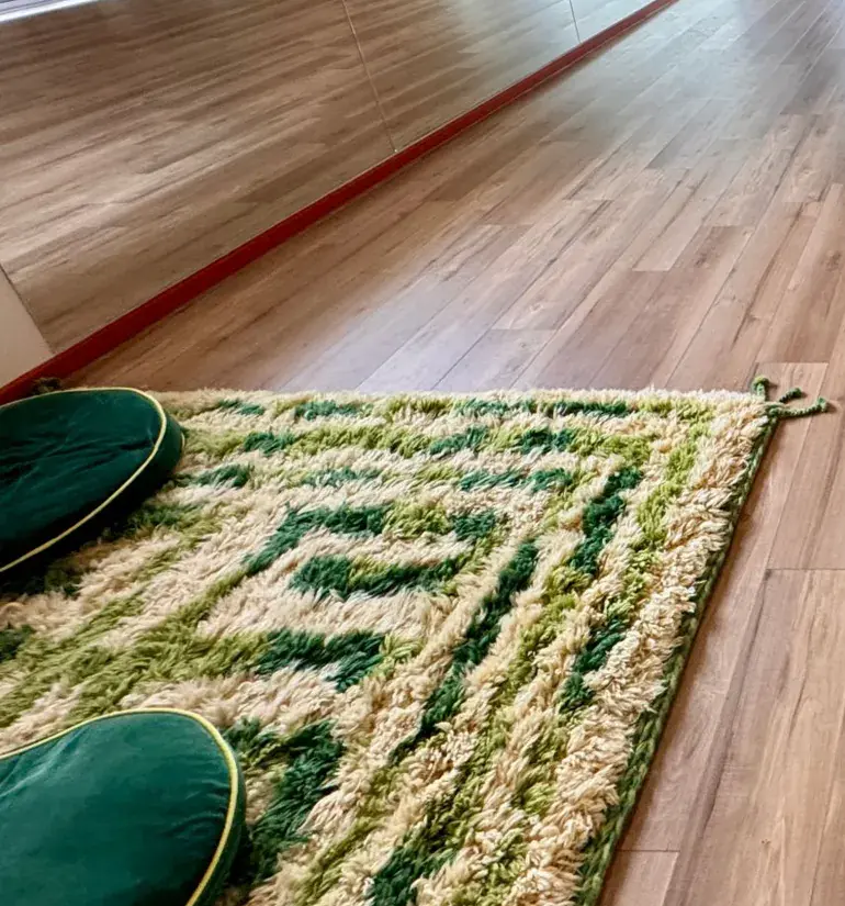 The studio upstairs: the green shag rug and floor cushions on the timber floor